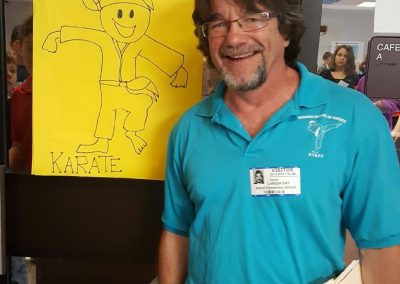 bill taylor standing next to a kid's drawing of him